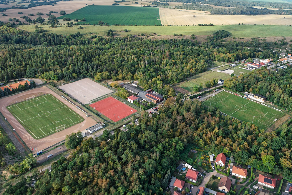 Luftaufnahme der Sportstätten des FC Hettstedt mit mehreren Fußballplätzen und angrenzendem Waldgebiet